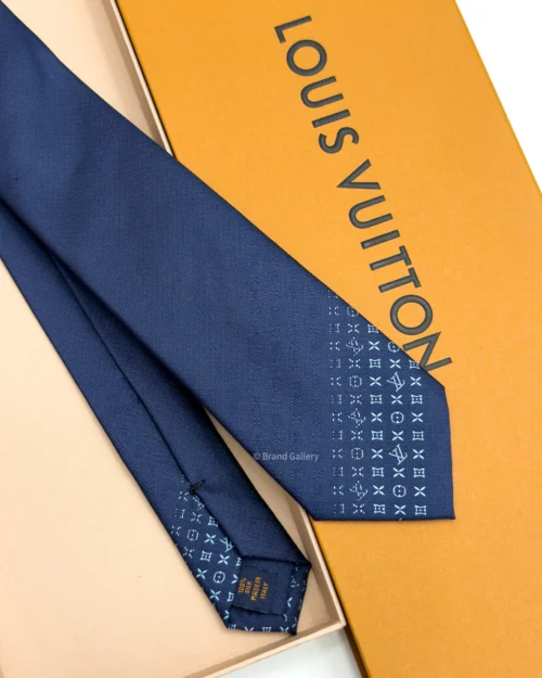 Blue silk tie with tonal geometric pattern and light blue detailing near the tip