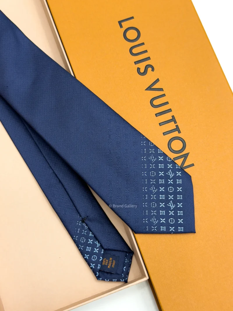 Blue silk tie with tonal geometric pattern and light blue detailing near the tip