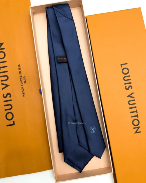 Navy blue solid silk tie with subtle light blue motif near the tip