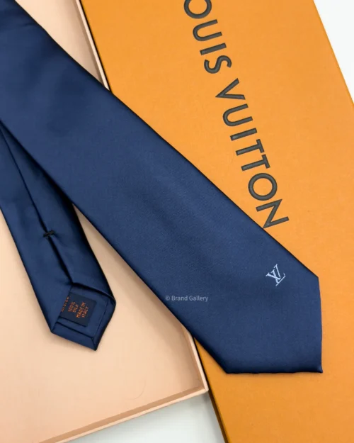 Navy blue solid silk tie with subtle light blue motif near the tip