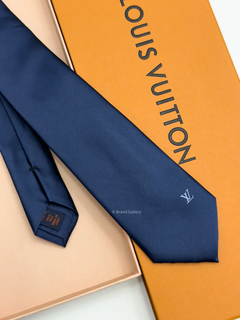 Navy blue solid silk tie with subtle light blue motif near the tip